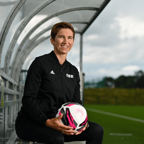 Michelle O Neill International Football FIFA Assistant Referee sitting in a football field holding a soccer ball in her hands