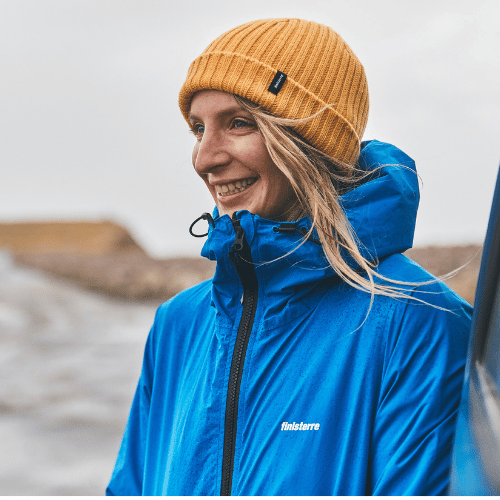 Easkey Britton on a beach wearing a blue jacket and yellow hat Irish Surfer and Marine Social Scientist